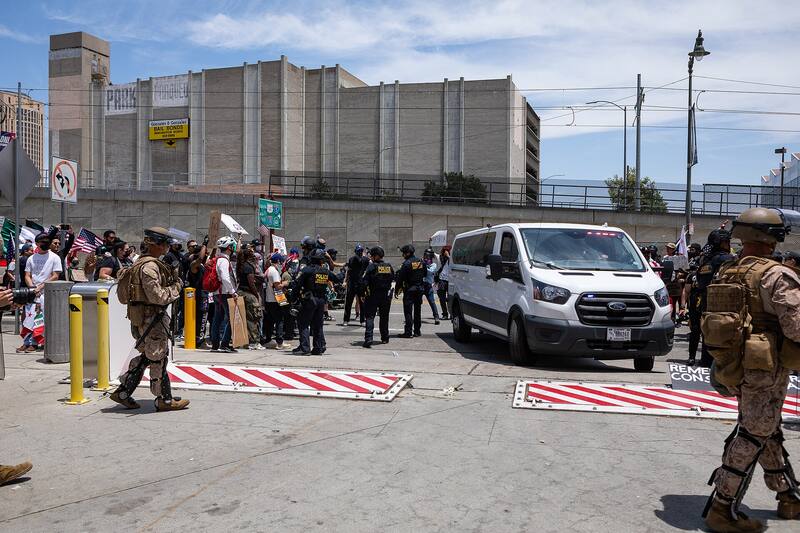 Soldiers guarding an ICE vehicle from protesters, June 2025